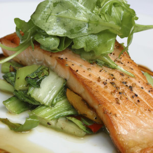 Food is pan-seared fillet of salmon with slow roasted peppers and pak choi.