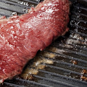 Bloody beef steak on grill pan background