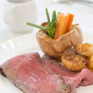 Traditional roast beef dinner with yorkshire puddings and vegetables.