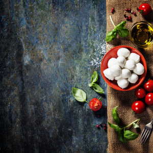 Cherry tomatoes, basil leaves, mozzarella cheese and olive oil for caprese salad. Lots of copy space